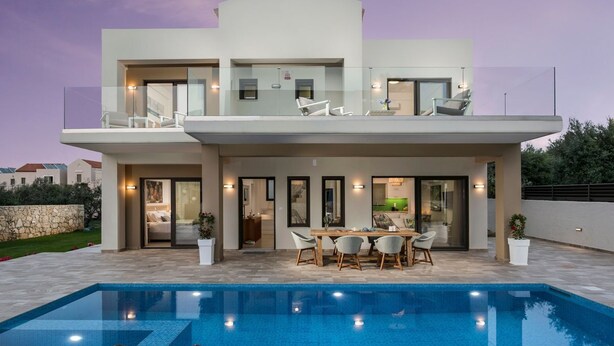 Ein modernes, zweistöckiges Haus mit Swimmingpool, Essbereich im Freien und einem Balkon mit Sitzgelegenheit.