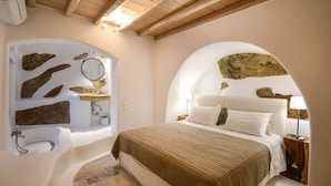 Un dormitorio con una cama grande, una bañera empotrada y decoración de paredes de piedra.