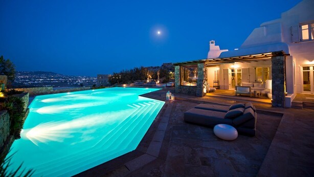 A modern outdoor pool area with a clear view of the city at dusk. - Villa Charoite - Six Bedroom Villa, Sleeps 12 (Thira)