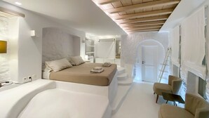 A modern bedroom with a large bed, a wooden ceiling, and a walk-in closet. - Villa Charoite - Six Bedroom Villa, Sleeps 12 (Thira)