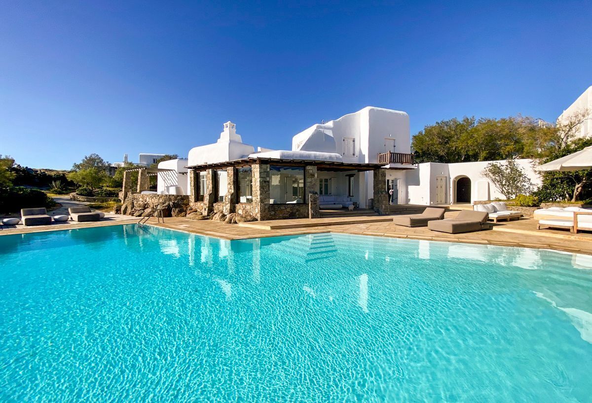 A clear blue pool with lounge chairs and a stone structure.