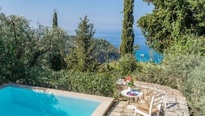 A pool with a stone deck, surrounded by greenery and overlooking a scenic view of the sea. - Villa Arithmos - Three Bedroom Villa, Sleeps 6 (Lefkada)