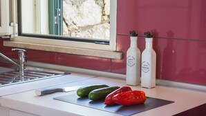 A kitchen counter with a knife, cucumbers, and red peppers. There are two bottles labeled "Country Home Olive Oil" and "Country Home Vinegar" on the counter. - Villa Arithmos - Three Bedroom Villa, Sleeps 6 (Lefkada)