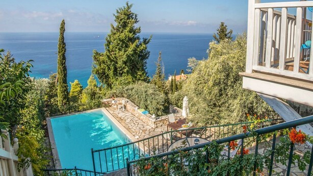 A pool with a stone deck, surrounded by greenery and a view of the sea. - Villa Arithmos - Three Bedroom Villa, Sleeps 6 (Lefkada)