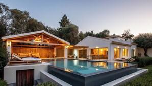 Et moderne hus med swimmingpool, udendørs siddepladser og en overdækket terrasse.