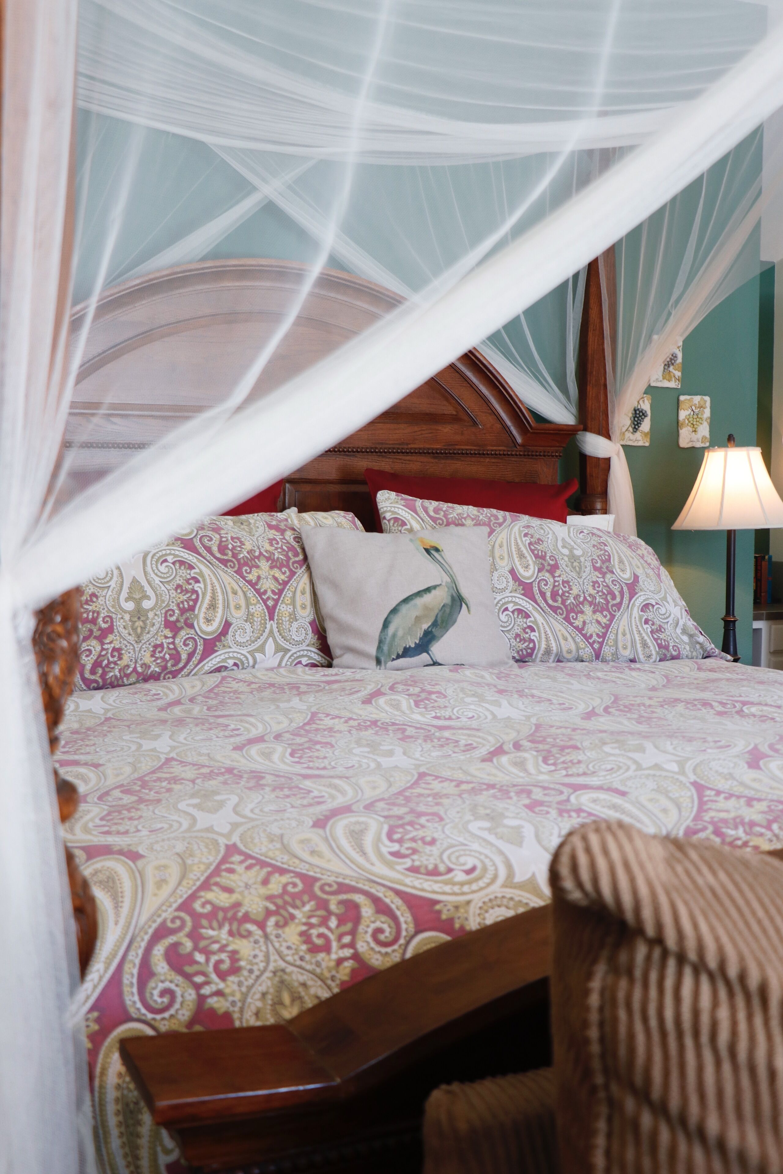 A bed with a canopy, patterned bedding, and a wooden headboard.