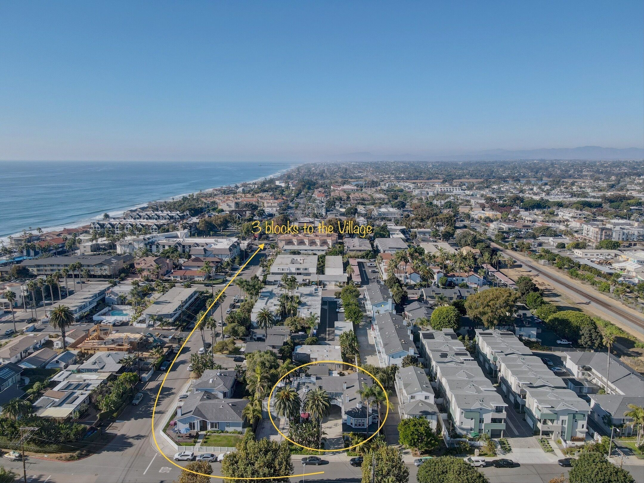 A residential area with a row of townhouses, a street, and a view of the ocean.