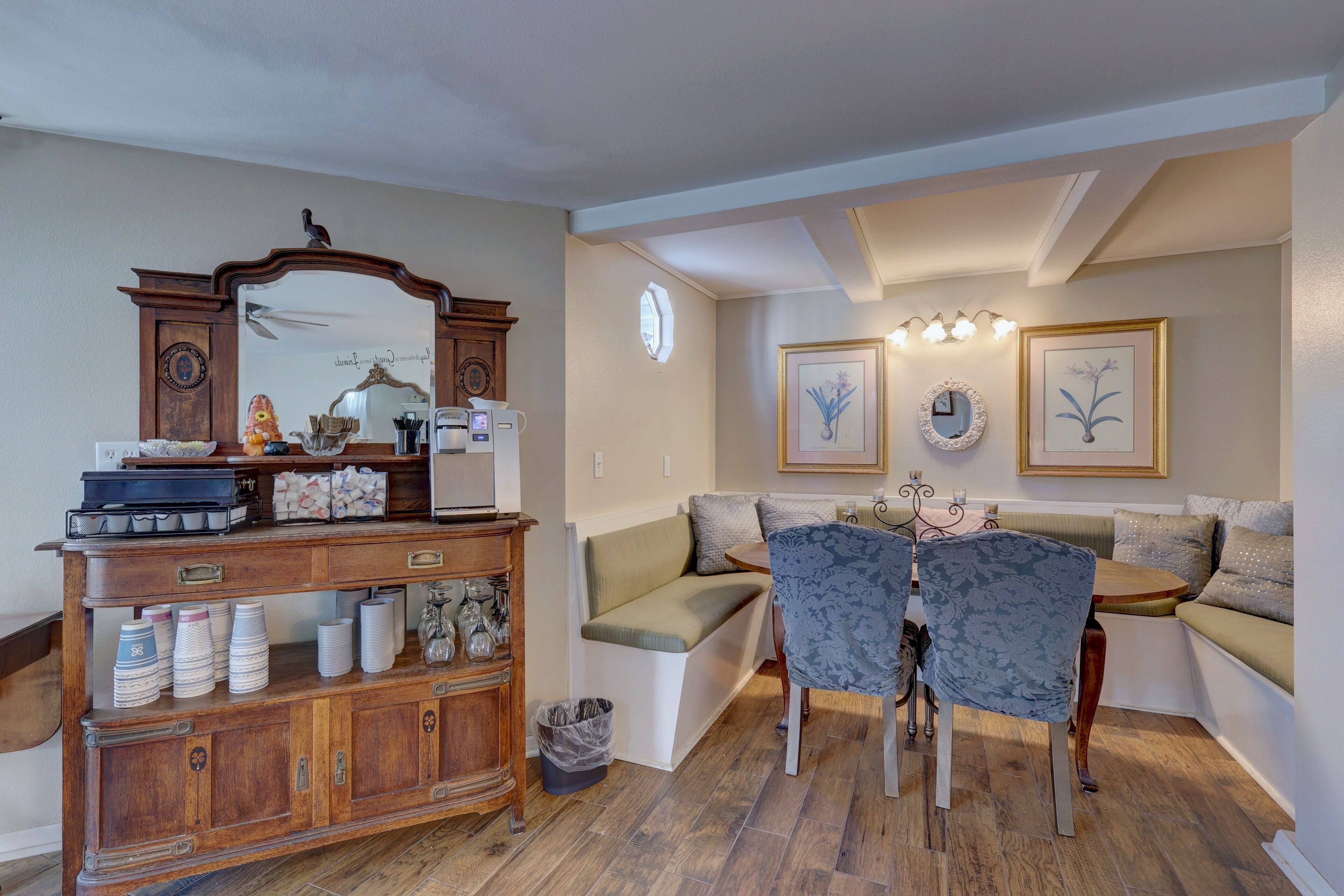 A cozy living room with a wooden cabinet, a bench, and a dining table with chairs.