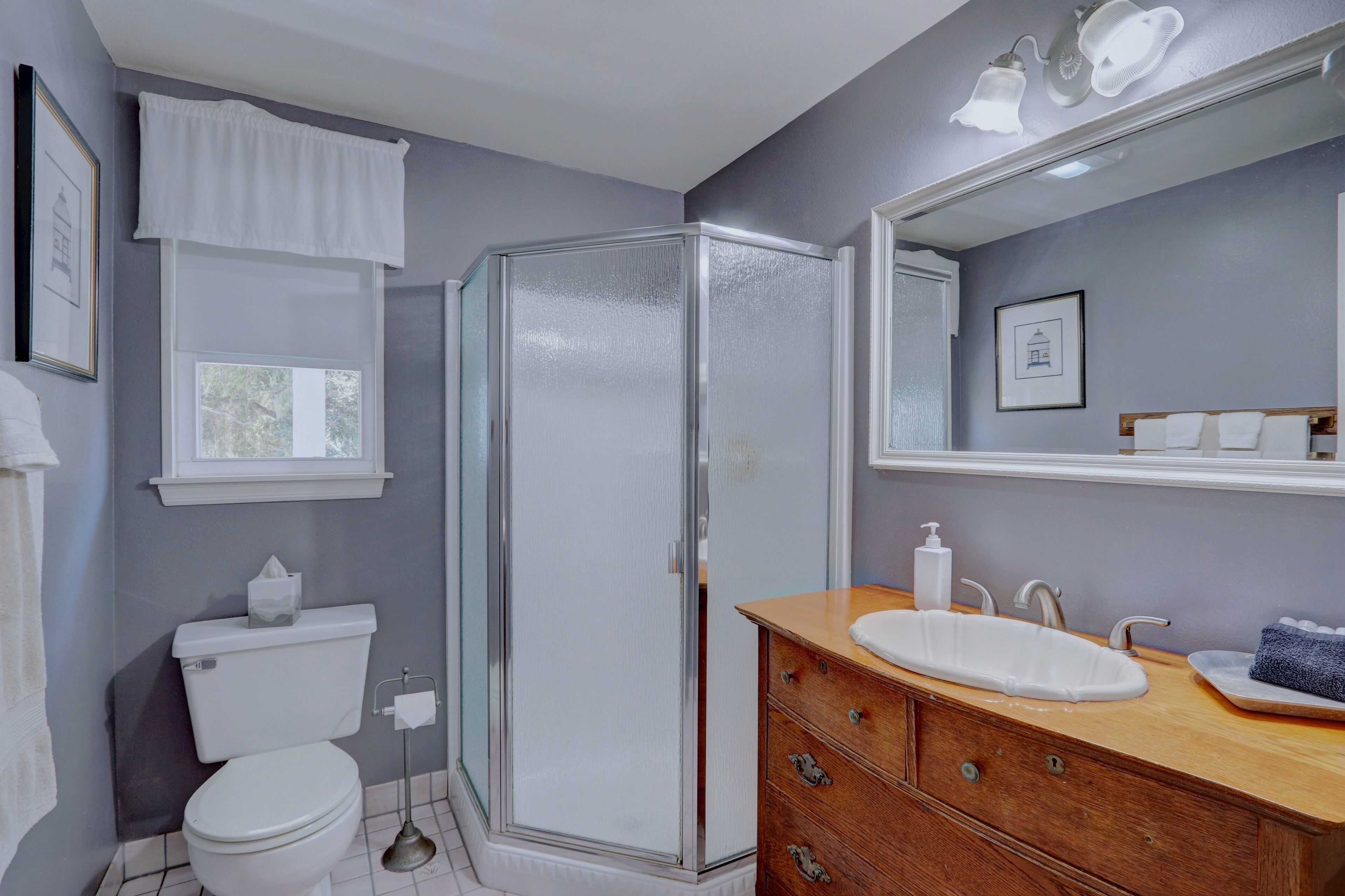 A bathroom with a toilet, a glass shower enclosure, a vanity with a sink, and a mirror.