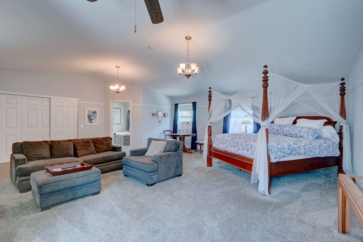 A bedroom with a four-poster bed, a sofa, a chair, and a small table.