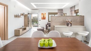 Un espace repas moderne avec une table en bois, des chaises blanches et une assiette de pommes vertes.
