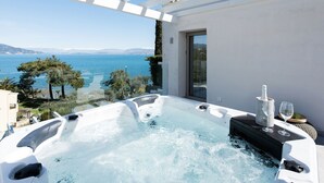 A hot tub with a glass table and wine glasses, overlooking a scenic view of the sea and mountains. - Villa Chloris - Three Bedroom Villa, Sleeps 8 (Kontokali)