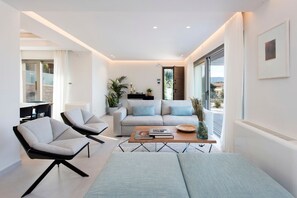 A modern living room with a sofa, two armchairs, a coffee table, and a dining area with a table and chairs.