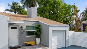 Une maison moderne à l’extérieur blanc, avec un garage et un petit porche à l’avant, accessible par quelques marches.