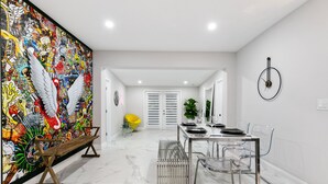 Un espace repas moderne agrémenté d’une fresque murale, d’un banc, d’une table à manger avec des chaises et d’une plante en pot.