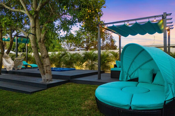 A patio area with a hammock, outdoor seating, and a covered seating area.