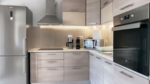 Una cocina moderna con electrodomésticos de acero inoxidable, armarios de madera y un piso con patrón de espiga.