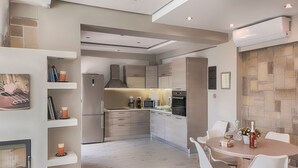 Una cocina moderna con electrodomésticos integrados, una zona de comedor con una mesa redonda y sillas, y una pared de acento de piedra.