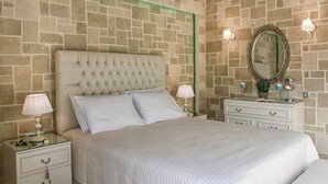 Un dormitorio con una cama grande, dos mesitas de noche con lámparas, un aparador y un espejo en la pared.