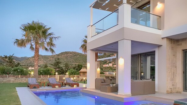 Una casa moderna con piscina, mobiliario de exterior y vistas a las colinas.