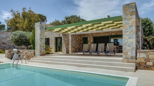 Ein Steinhaus mit Pool, Sitzgelegenheiten im Freien und einer Pergola.