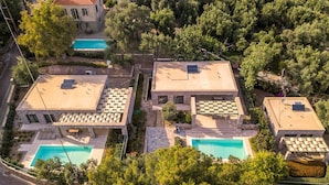 Ein Wohnhaus mit mehreren Swimmingpools, einer Steinaußenfassade und einem üppigen Garten.