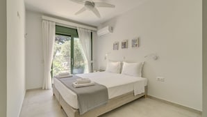Ein Schlafzimmer mit Bett, Deckenventilator, Klimaanlage und einem fenster mit Vorhängen.