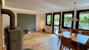 Une cuisine moderne dotée d’une cuisinière intégrée, de planchers en bois et de grandes fenêtres offrant une vue sur la verdure.