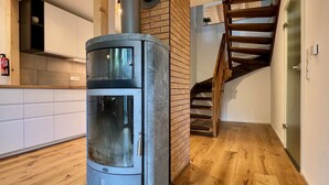 Une cuisine moderne dotée d’un poêle à bois encastré, d’un escalier en bois et d’un îlot central.
