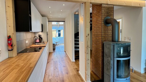 Une cuisine moderne avec un plancher en bois, une cuisinière encastrée et un extincteur.