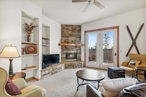 Una sala de estar con chimenea, televisor y zona de estar.