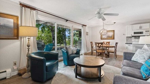 A modern living room with a dining table, sofas, and a ceiling fan. - Whitefish Lake Condo, 14BD, hillside! (White)