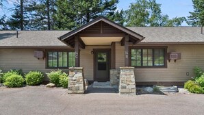 A two-story building with a brown roof, stone pillars, and a front door. - Whitefish Lake Condo, 14BD, hillside! (White)