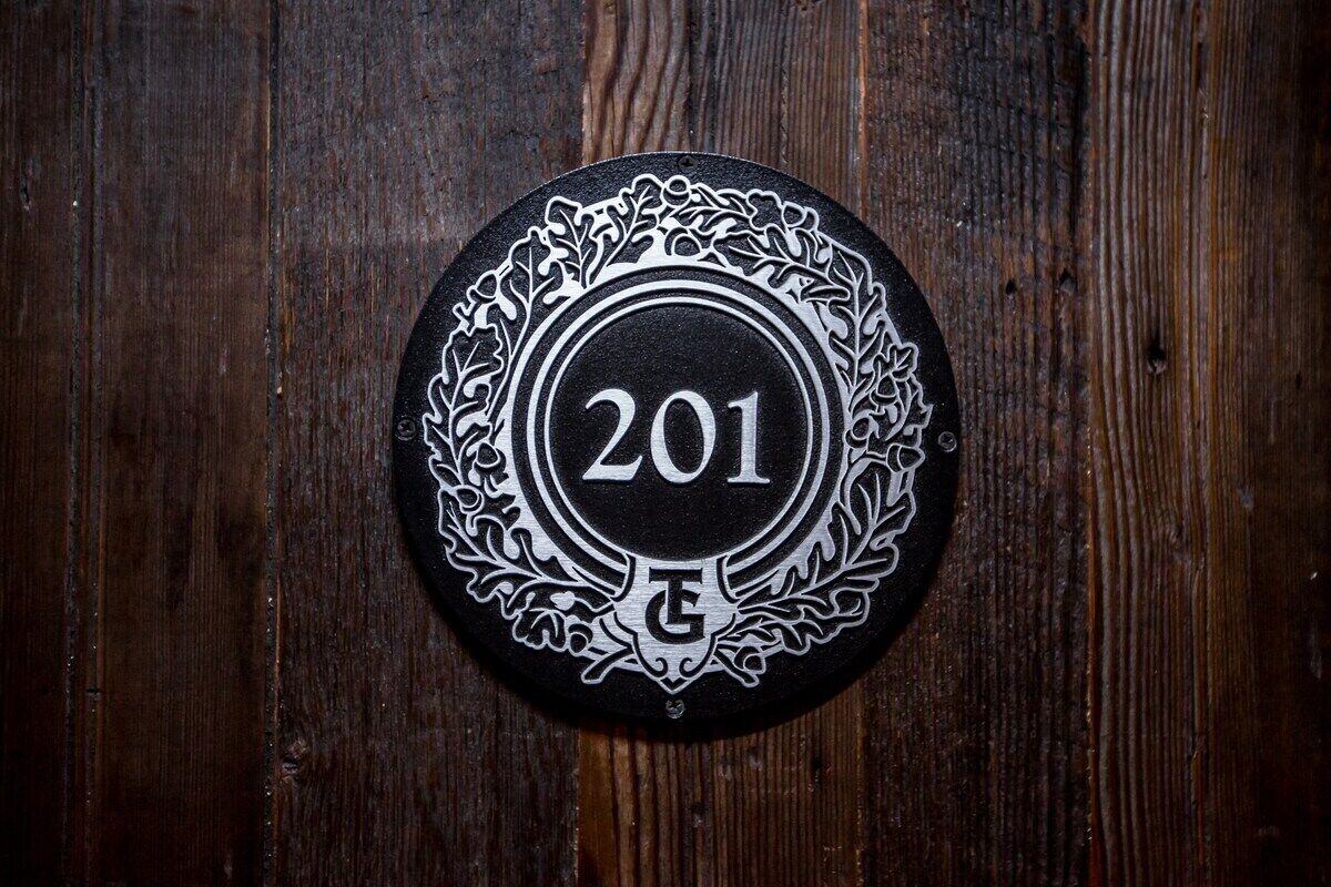 Een rond object met het nummer '201' en een decoratieve rand, liggend op een houten oppervlak.