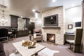 Cozy living room with a fireplace, television, and dining area, featuring a comfortable seating space and a well-equipped kitchen.