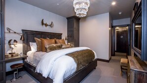 Un dormitorio con una cama grande, una araña de cristal, un cabecero de madera y una mesita de noche con lámpara.
