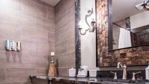 Un baño con tocador de madera, un espejo grande y zona de ducha.