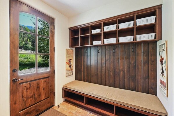 A wooden bench with storage baskets, a door with a window, and a poster on the wall.