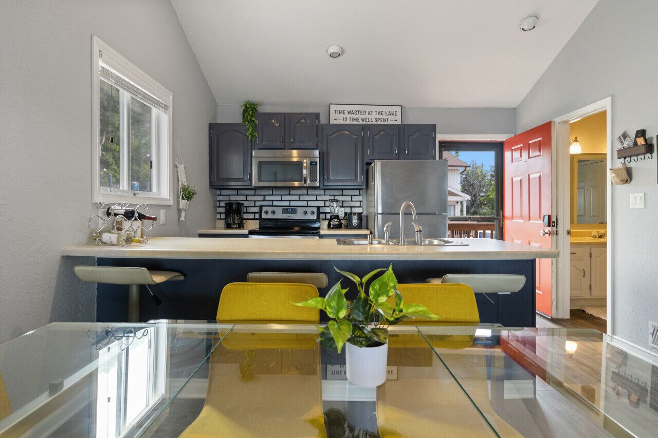 Una cocina moderna con gabinetes grises, un microondas de acero inoxidable y una puerta roja.