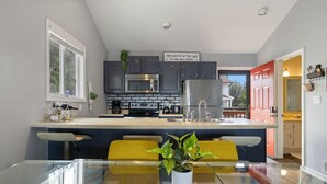 Una cocina moderna con gabinetes grises, un microondas de acero inoxidable y una puerta roja.
