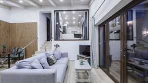 A modern living room with a grey sofa, a small white table, and a wooden wall. - Cubo's Finca Las Palmeras / Private pool / Free Wifi (Alhaurin de la Torre)