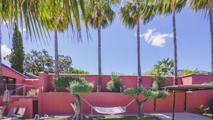 A swimming pool with a red wall, palm trees, and a hammock. - Cubo's Finca Las Palmeras / Private pool / Free Wifi (Alhaurin de la Torre)