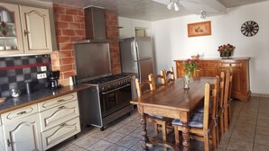 A kitchen with a stove, oven, refrigerator, and wooden dining table with chairs.
