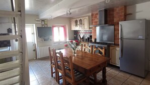 A kitchen with a dining table, chairs, a refrigerator, a stove, and cabinets.
