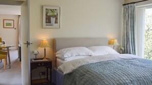 Et soveværelse med en seng, to sengeborde, en lampe på hvert bord, et billede i ramme og et vindue med gardiner.