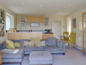 A modern living room with a grey sofa, ottoman, and a dining area with a yellow chair. - Dewsnap Spring- RTT4 (Chinley, near Chapel-en-le-Frith)