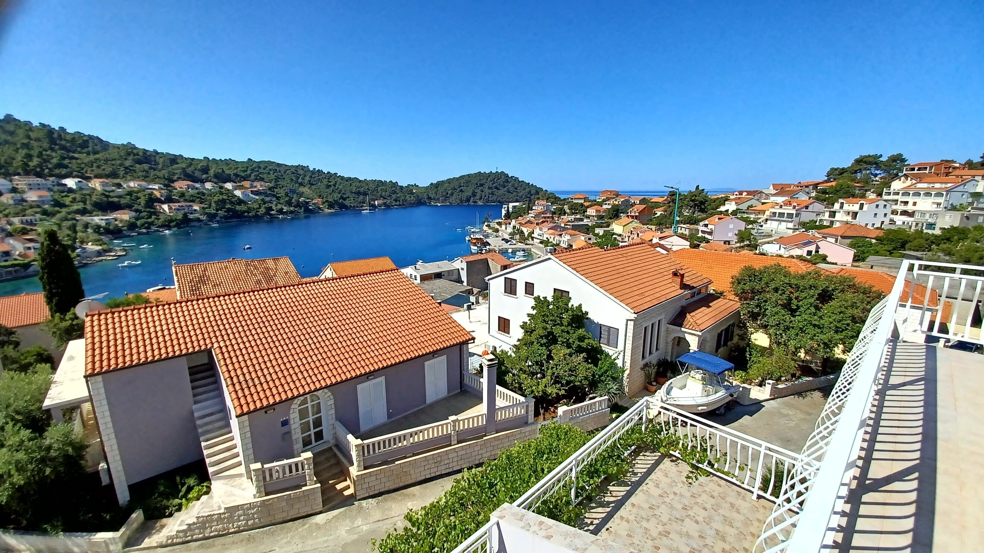 Eine Küstenstadt mit terrakottafarbenen Dächern, einem Hafen und freiem Blick auf das Meer.