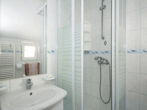 Une salle de bain avec une douche à parois de verre, un lavabo et un miroir.