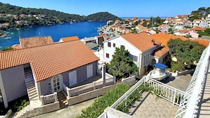 A coastal town with terracotta-roofed buildings, a clear blue sea, and a hilly backdrop. - Bertie's Lodge - Two Bedroom Apartment with Terrace and Sea View (Smokvica)