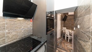 A modern kitchen with a black stove, stainless steel appliances, and a stone backsplash. - Apartments Keka - Studio Apartment (Kastel Sucurac)